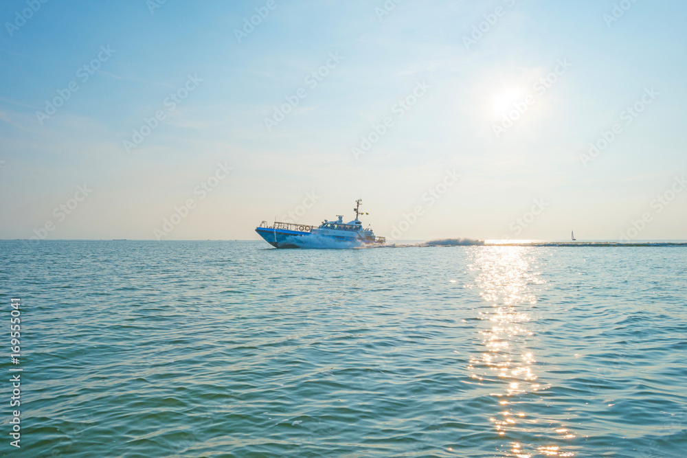 Obraz premium Boat sailing on a lake at sunset in summer