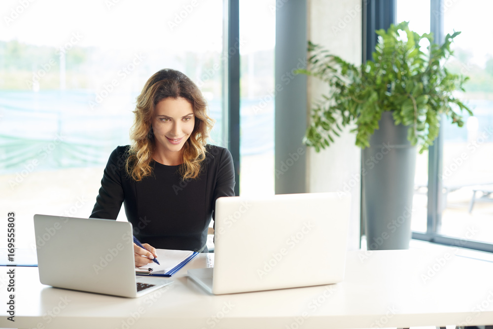 Professional woman at work. Shot of a financial consultant businesswoman working on laptop and doing some paperwork at the office. Professional woman at work. Shot of a financial consultant businesswoman working on laptop and doing some paperwork at the office.