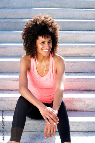 Beautiful healthy woman smiling with headphones and sitting on steps
