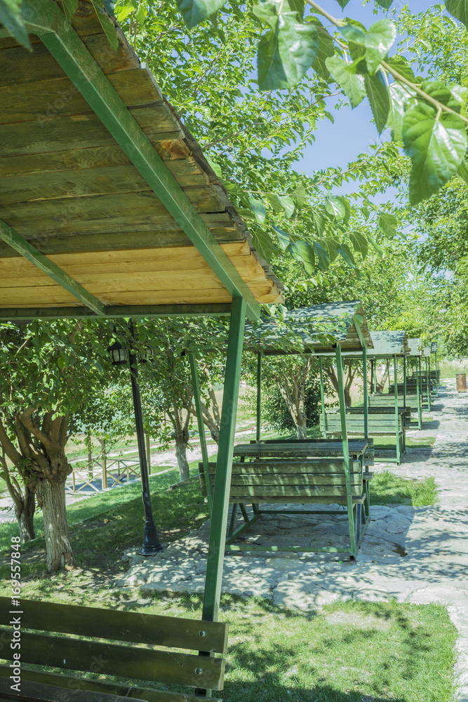 Series of green bench huts in a sunny outdoors park