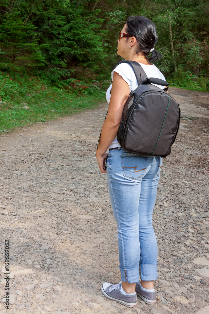 Back View Shot of Young Woman with Backpack Standing in front of Forest Back View Shot of Young Woman with Backpack Standing in front of Forest