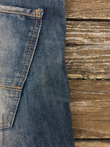 Close-up shot of blue jeans on rough wooden background.