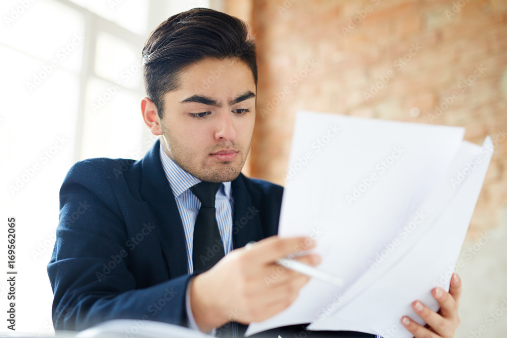 Young employee looking through financial papers Young employee looking through financial papers