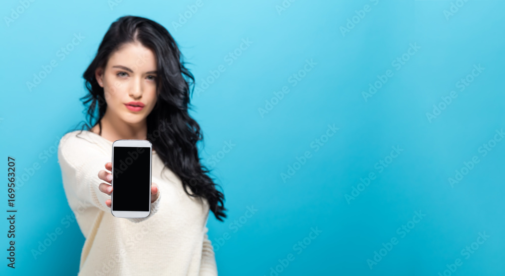 Young woman holding out a cellphone in her hand Young woman holding out a cellphone in her hand
