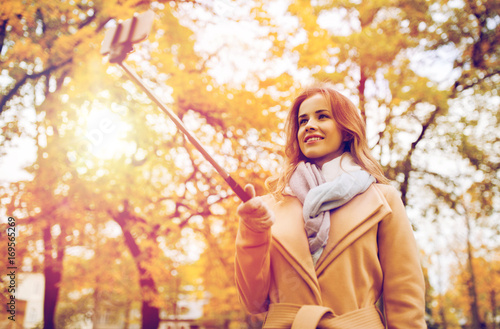 woman taking selfie by smartphone in autumn park