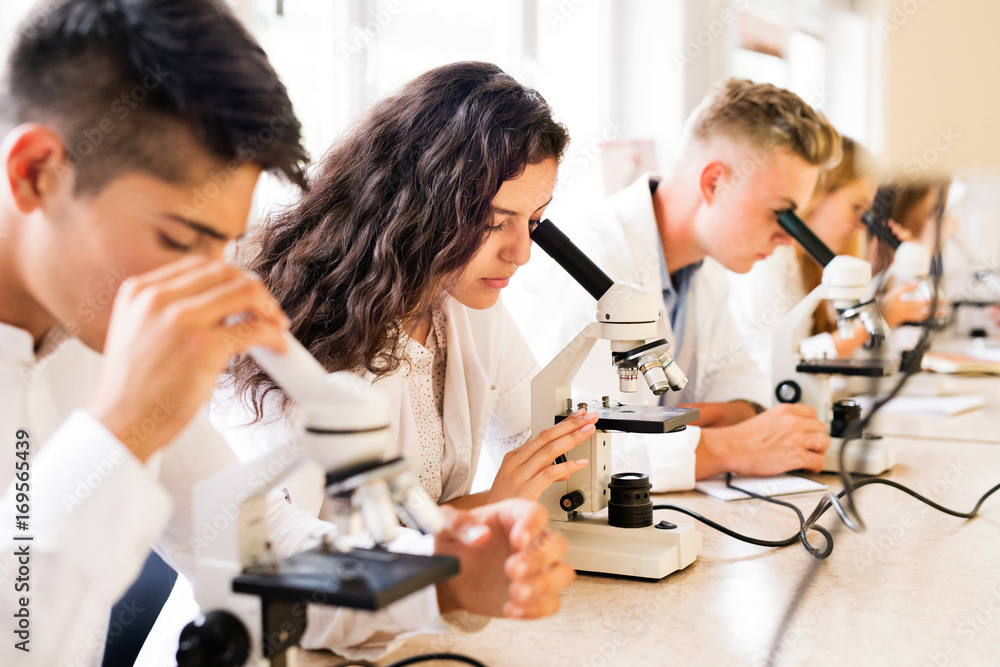 © Halfpoint - Beautiful high school students with microscopes in laboratory.