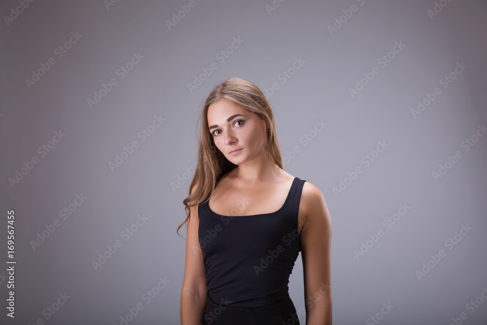 woman girl in black dress studio portrait. Blonde hair model female in black short dress over gray background woman girl in black dress studio portrait. Blonde hair model female in black short dress over gray background