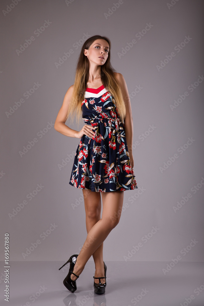 Beautiful girl in dress with floral print on grey background Beautiful girl in dress with floral print on grey background