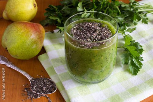 Healthy drink: green smoothies with pear, parsley and chia seeds on the wooden background