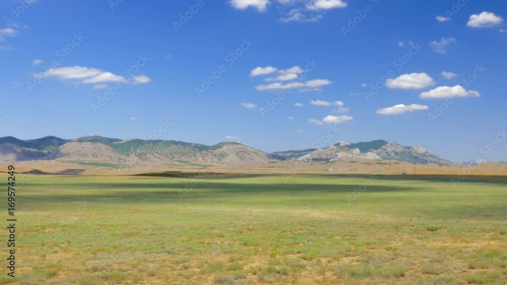 Landscape of steppes and hills on blue sky background, time lapse / Steppe and mountains against blue sky with floating white clouds, time lapse Landscape of steppes and hills on blue sky background, time lapse / Steppe and mountains against blue sky with floating white clouds, time lapse