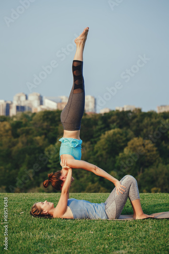 Two Women Finding Balance In A Yoga Pose by Stocksy Contributor ISO DUO  - Stocksy