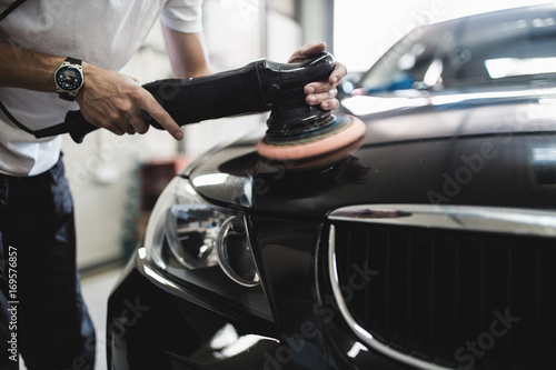 Car detailing - Hands with orbital polisher in auto repair shop. Selective focus. © Dusko