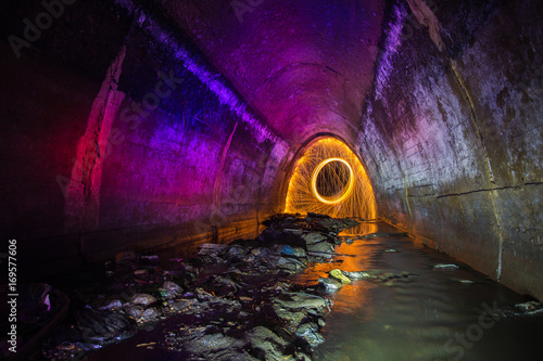 Sewer tunnel illuminated by color lanterns and freezelight using spinning burning steel wool and pyrotechnics photo