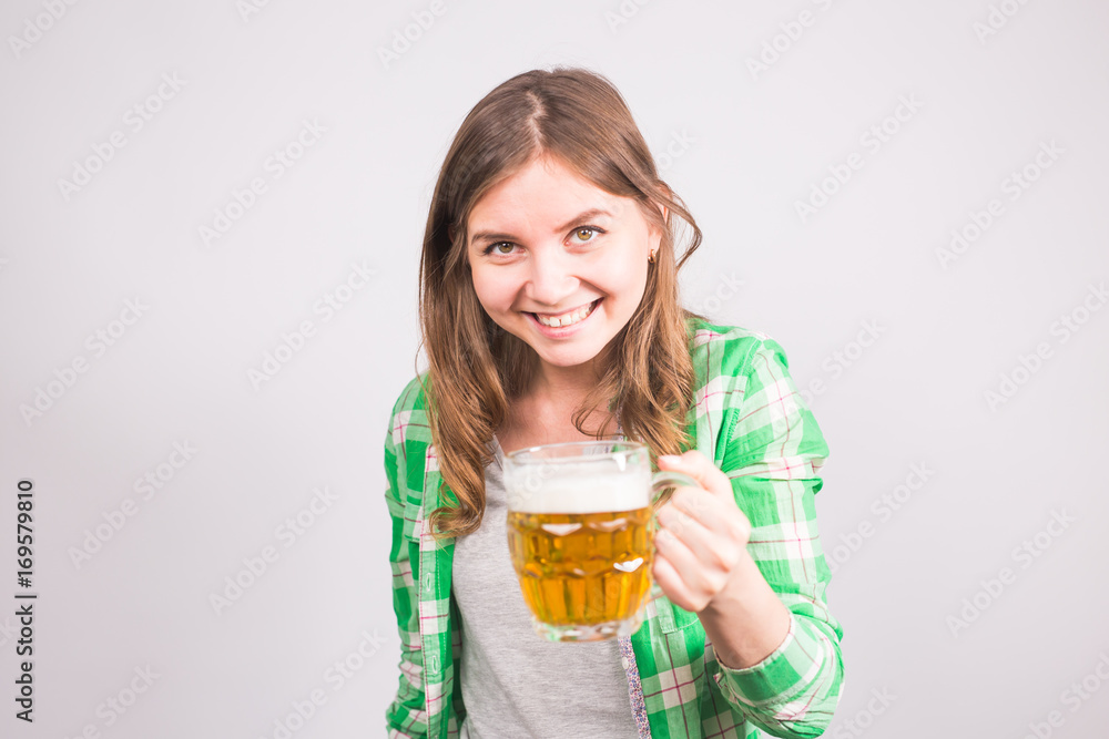 Cheerful young woman holding a beer mug full of beer and smiling on white background Cheerful young woman holding a beer mug full of beer and smiling on white background