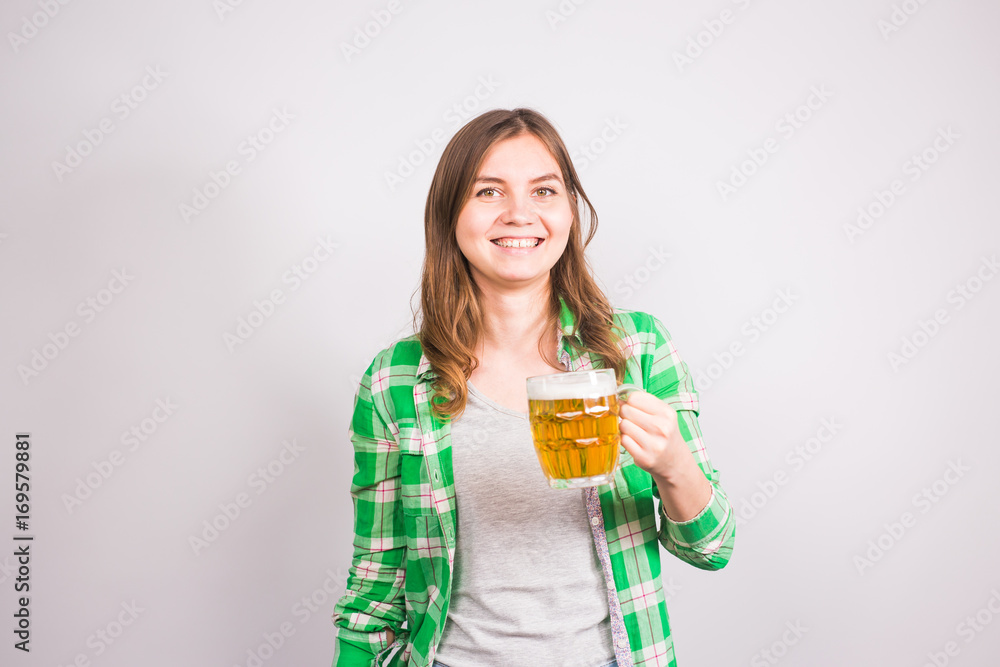 Cheerful young woman holding a beer mug full of beer and smiling on white background Cheerful young woman holding a beer mug full of beer and smiling on white background