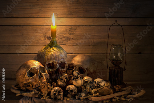 Human skulsl and pile bone with candle Light, Still life style onold wooden table