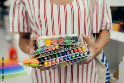 Mother choosing buying stationery in store preparing for first day in school. Closeup on buyer hands holding goods. Busy blurred shopping indoors background