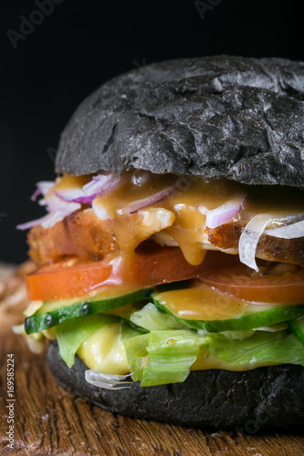 Fresh tasty burger on black background. Homemade Pork steak hamburger onion, tomato, lettuce and cheese with ingredients