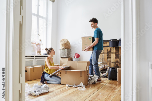 Couple Unpacking Cardboard Boxes At New Apartment photo