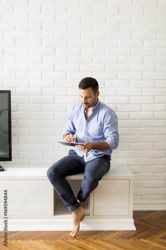 Happy man browsing in a tablet sitting on commode at home