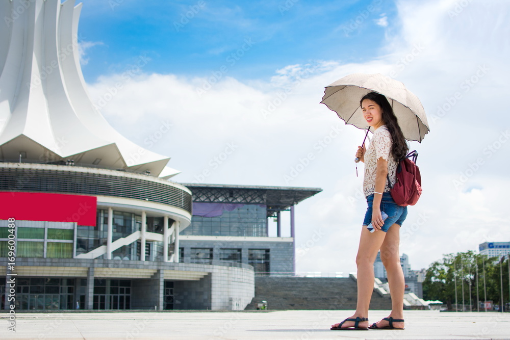 Asian tourist holding umbrella to protect from the sun