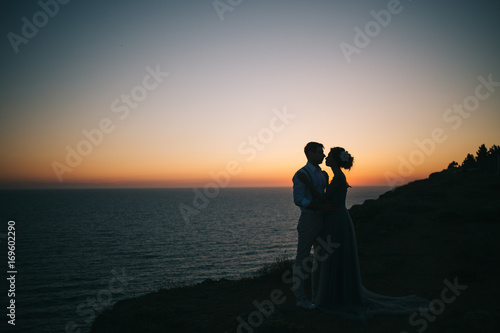 Beautiful sunset at sea, a man and a woman hugging and looking at each other, a love story