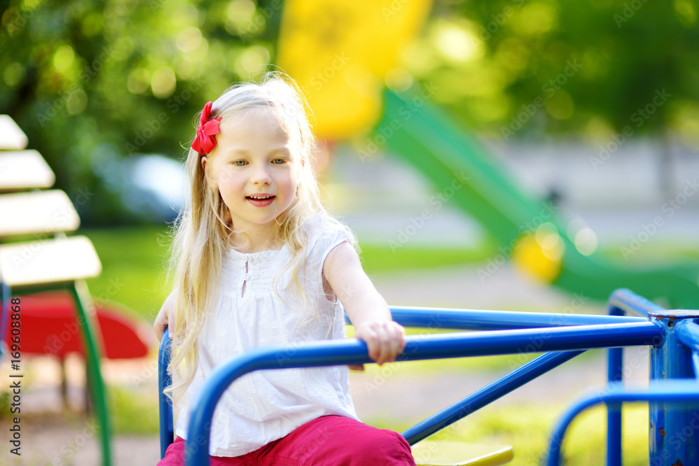 Cute little girl having fun on a playground outdoors in summer. Cute little girl having fun on a playground outdoors in summer.