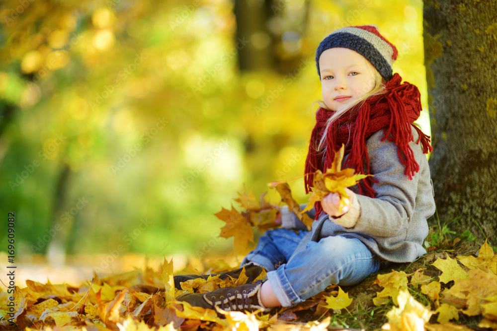 Cute little girl having fun on beautiful autumn day. Happy child playing in autumn park. Kid gathering yellow fall foliage. Cute little girl having fun on beautiful autumn day. Happy child playing in autumn park. Kid gathering yellow fall foliage.
