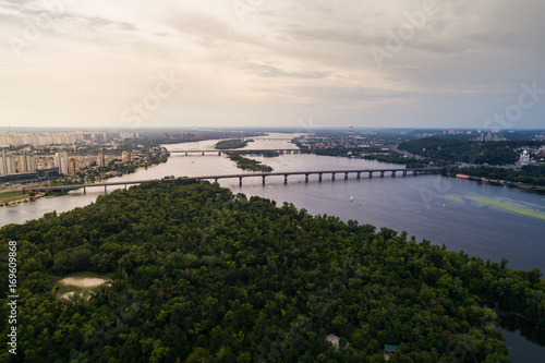 Panoramic view of Kiev city with the Dnieper River in the middle. Aerial view of the residential district and industrial Zone at sunset. Two banks of the river connected by bridges
