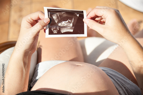 pregnant / Pregnant woman sitting in chair and watching a picture with ultrasound