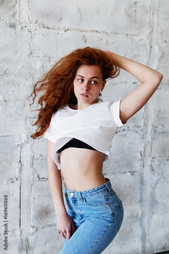 Model tests.Beautiful redhead girl with curly hair. Natural color. Dancing and moving on the background of light brick wall. Dynamics Model tests.Beautiful redhead girl with curly hair. Natural color. Dancing and moving on the background of light brick wall. Dynamics