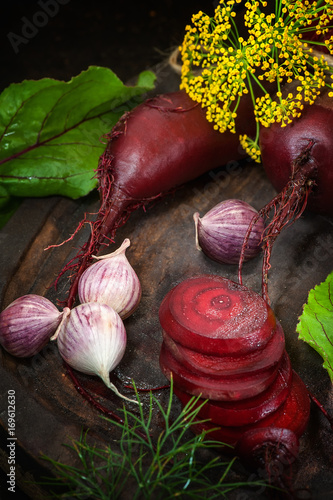 Sliced beets for making chips on a wooden Board with garlic and dill in a rustic style.