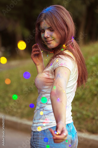 Lovely young woman covered with colorful Gulal powder holding garland