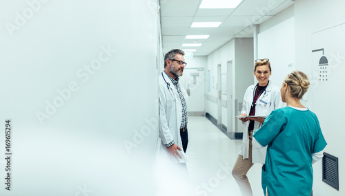 Medical team discussing in corridor at hospital photo