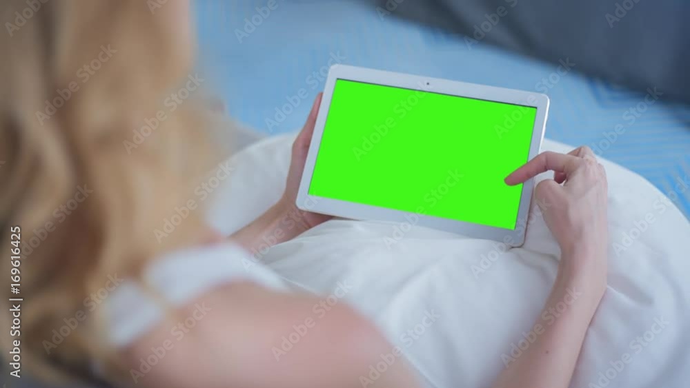 Young Woman in white top sitting on couch uses Tablet PC with pre-keyed green screen. Few types of gestures - scrolling up and down, tapping, zoom in and out. Perfect for screen compositing Young Woman in white top sitting on couch uses Tablet PC with pre-keyed green screen. Few types of gestures - scrolling up and down, tapping, zoom in and out. Perfect for screen compositing