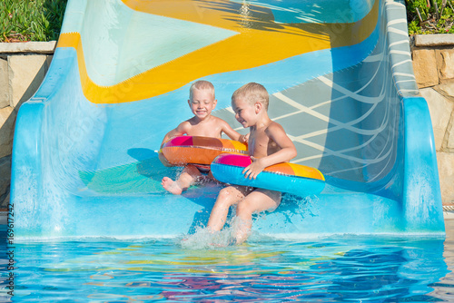 Two brothers in an inflatable rubber circles to hold hands and move down the water slide. 