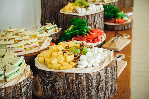 Outside Catering buffet table with a delicious food for guests of the event in rustic style. Service at business meeting, party, weddings. Selective focus, space for text photo