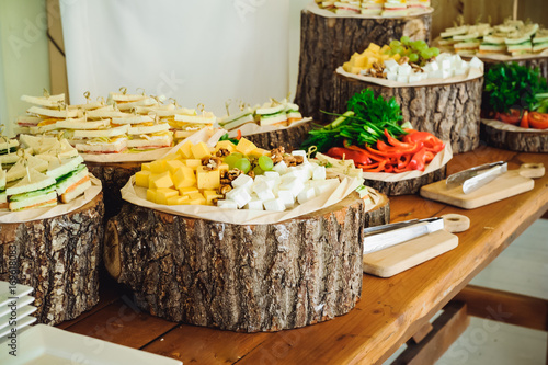 Outside Catering buffet table with a delicious food for guests of the event in rustic style. Service at business meeting, party, weddings. Selective focus, space for text photo