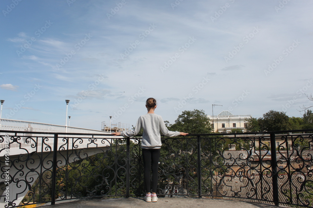 Obraz premium A young girl stands with her back on a viewing platform