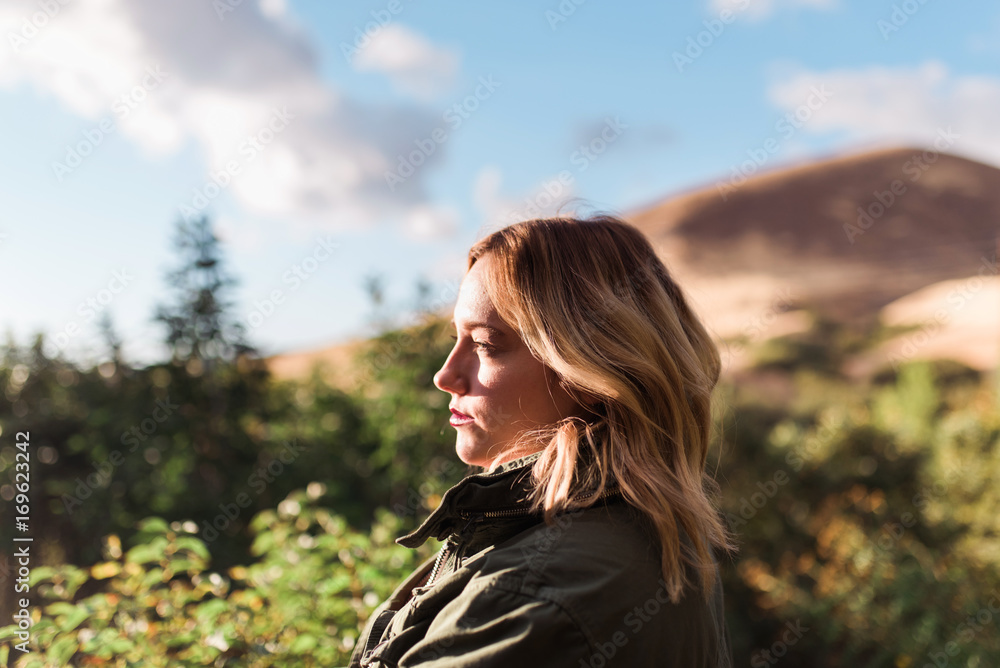 A woman standing in the sunlight in the mountains A woman standing in the sunlight in the mountains