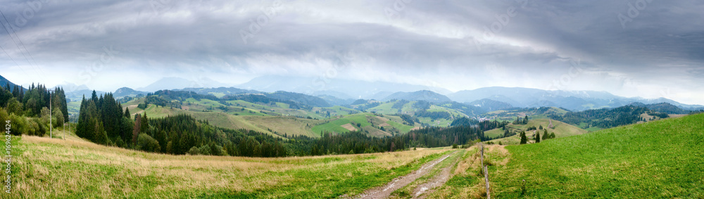 Summertime rural landscape banner, panorama - view at dirt road against the background of mountains Western Carpathians, Zilina Region in the Slovakia