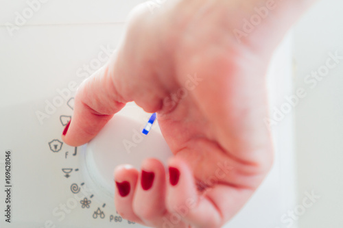 Woman s hand adjusting the knob of a washing machine