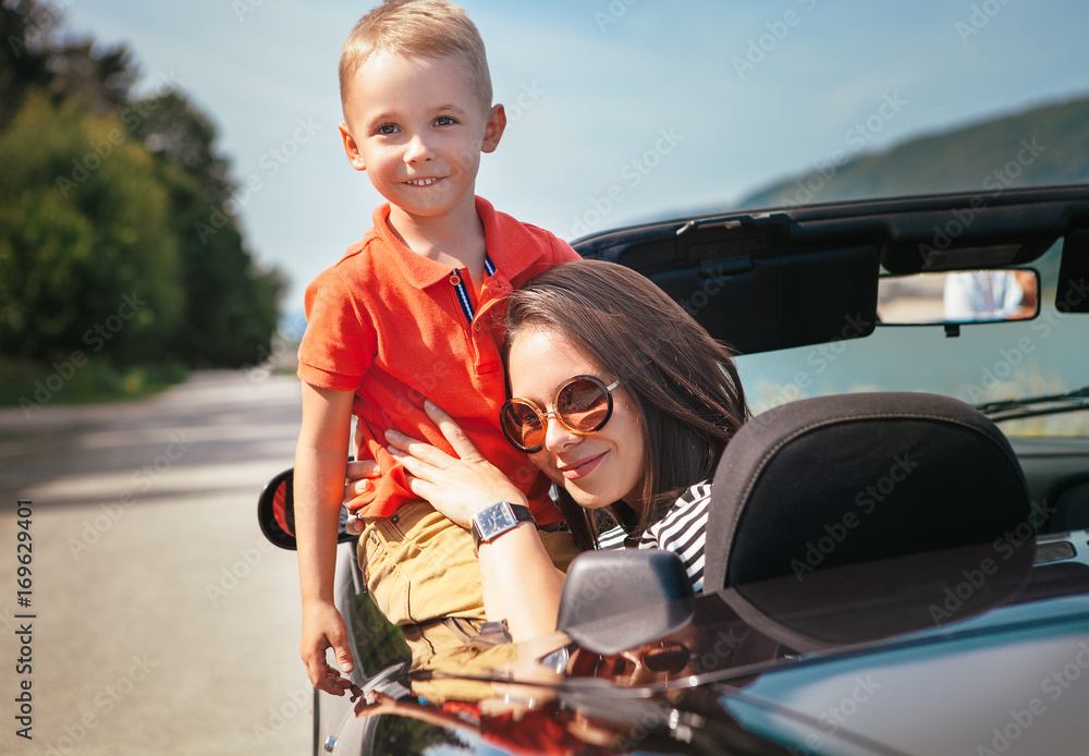 Mother and little son sitting in cabriolet car
