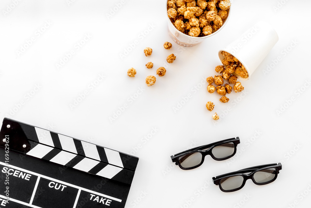 To go to the cinema. Clapperboard, glasses and popcorn on white background top view copyspace
