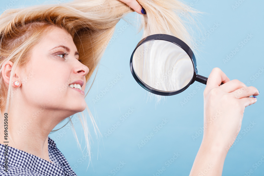 Woman looking at hair through magnifying glass Woman looking at hair through magnifying glass