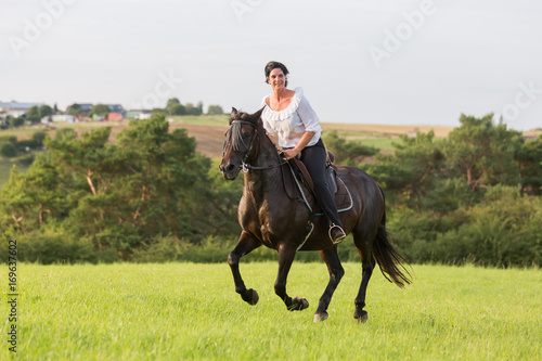 mature woman riding an Andalusian horse