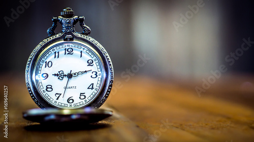 old antique pocket watch showing time on wooden floor with blurred background