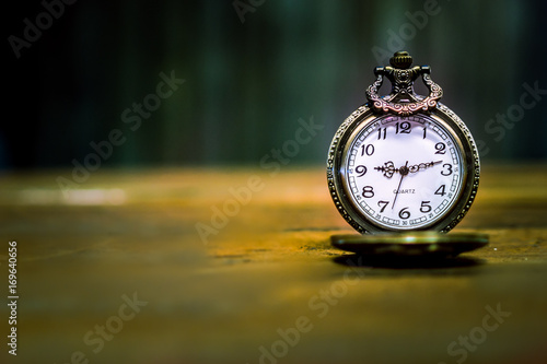 old antique pocket watch showing time on wooden floor with blurred background