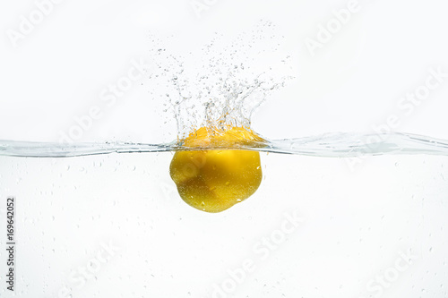 Lemon being dropped into water isolated on white
