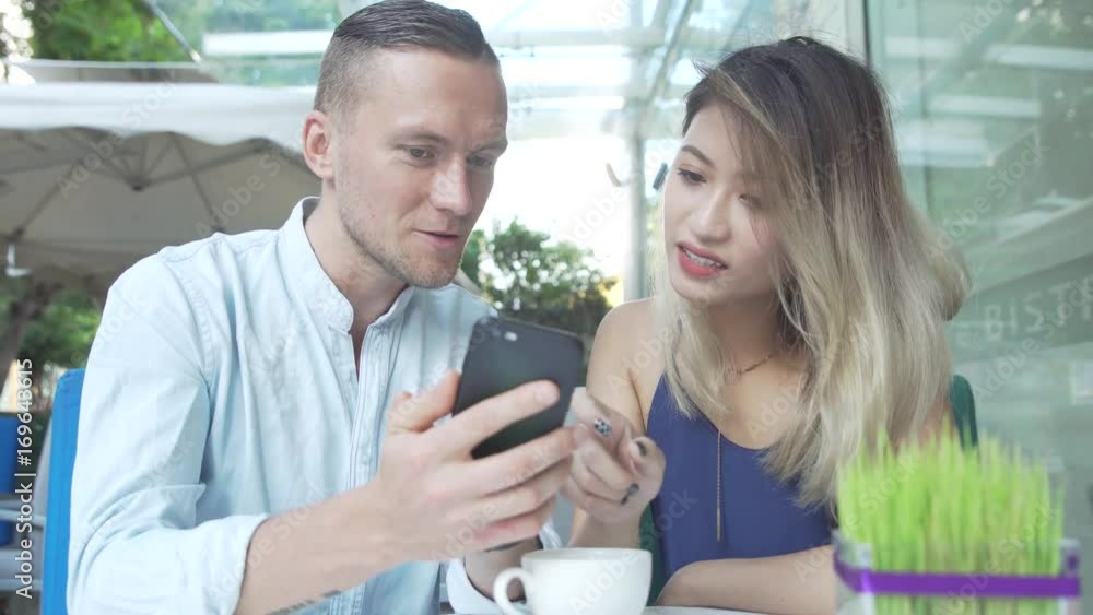 Multicultural couple using smartphone together Multicultural couple using smartphone together